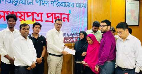 নওগাঁ জেলা প্রশাসনের পক্ষে শহীদ পরিবারের জন্য জাতীয় সঞ্চয় পত্র বিতরণ করেন জেলা প্রশাসক